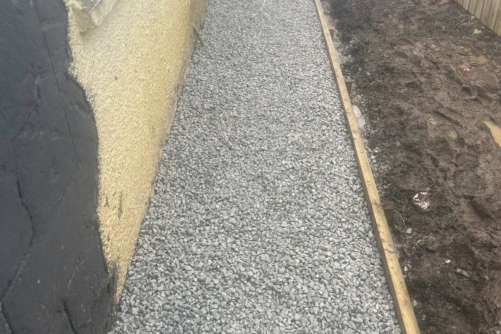 After: completed gravel path with timber edging laid alongside the house
